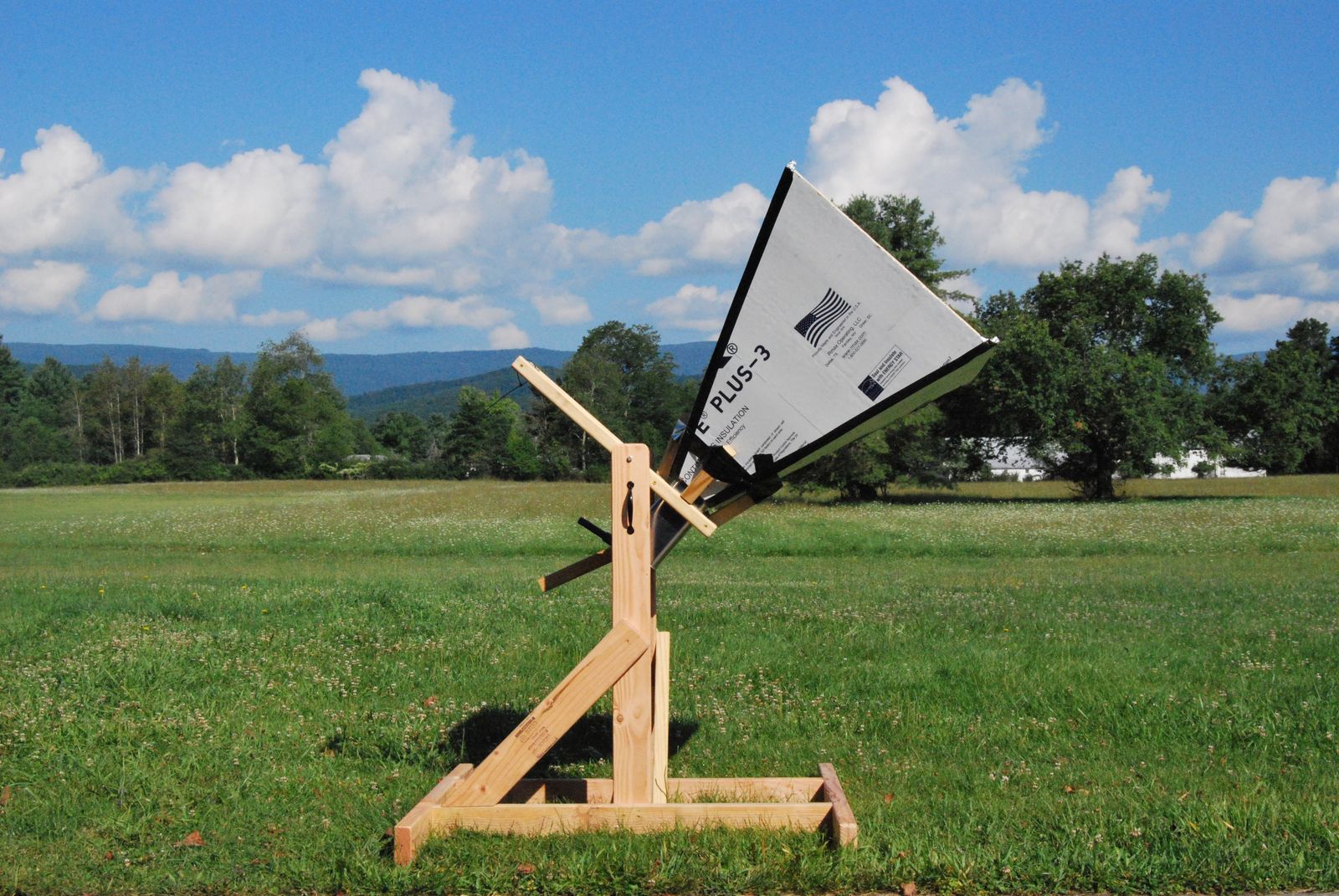 A completed horn antenna on its wooden mount standing in a field under a blue sky